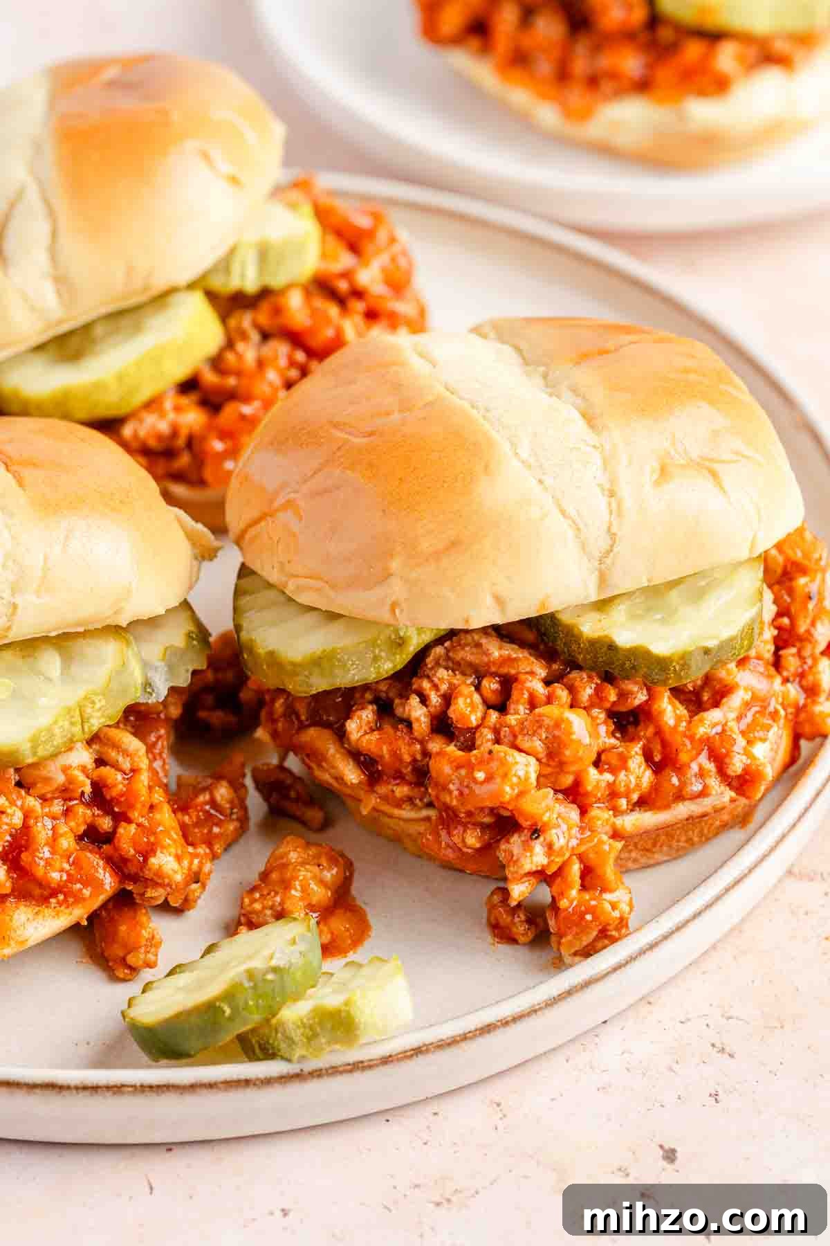 Ground Chicken Sloppy Joes with Tangy BBQ Sauce 2 chicken sloppy joes with pickles on plate.