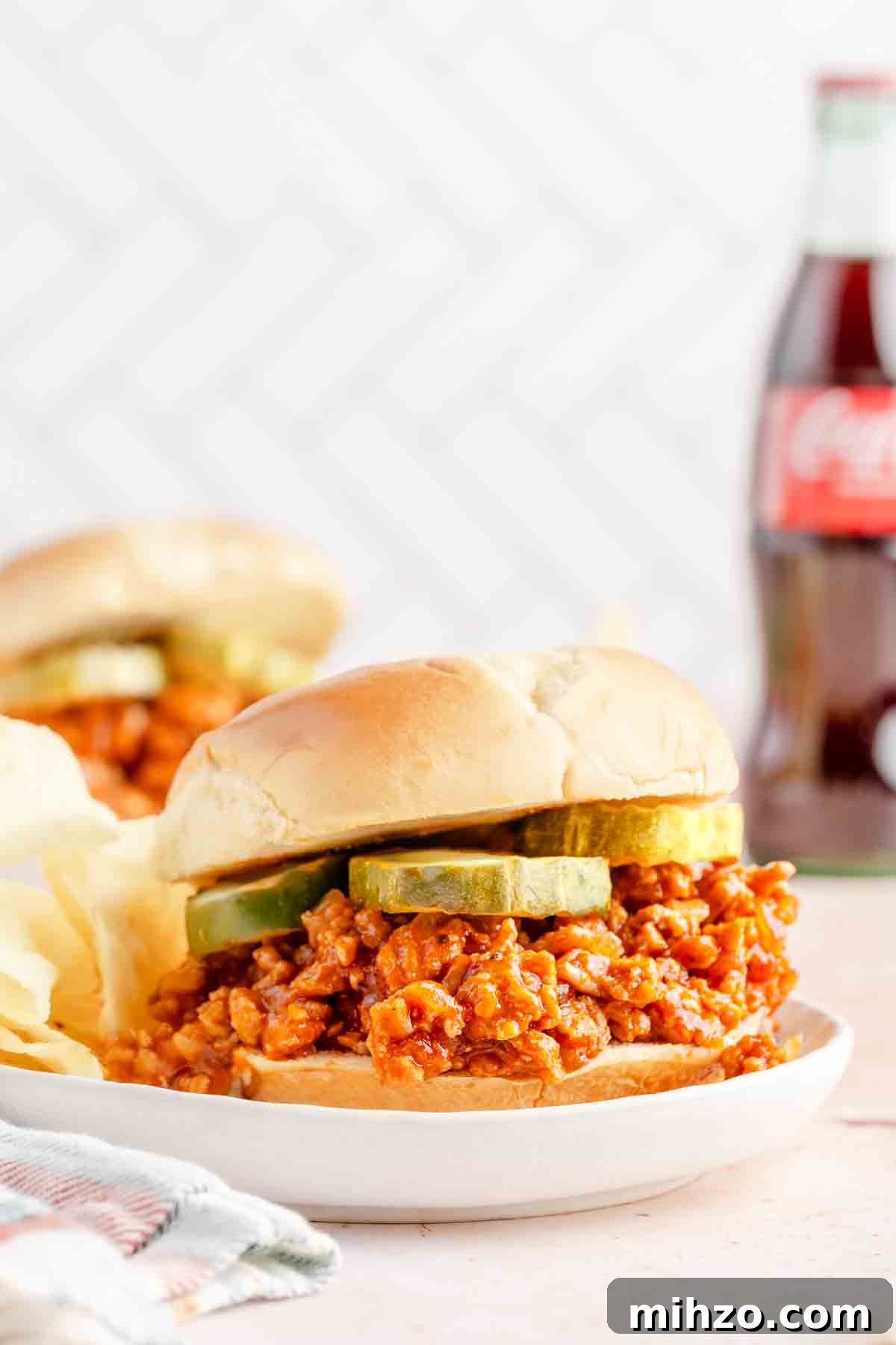 Ground Chicken Sloppy Joes with Tangy BBQ Sauce 8 sloppy joe made with ground chicken garnished with pickle slices on white plates.