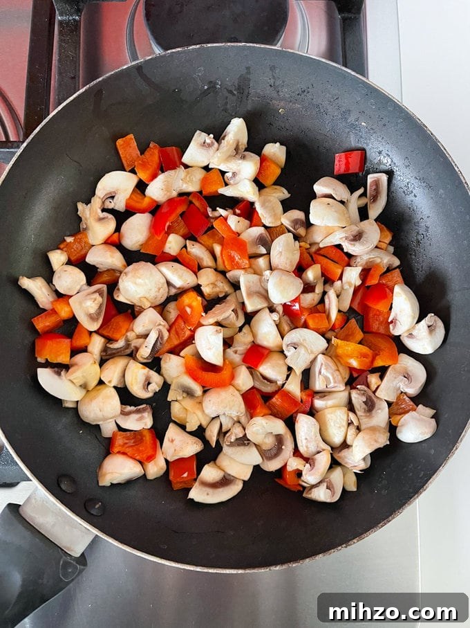 Cheesy Veggie Quesadillas with Roasted Peppers and Spinach 5 Mushrooms and peppers cooking in a frying pan.
