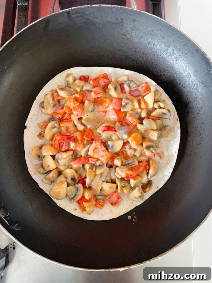 Cheesy Veggie Quesadillas with Roasted Peppers and Spinach 7 Cooked ingredients placed on top of a small tortilla in the frying pan.