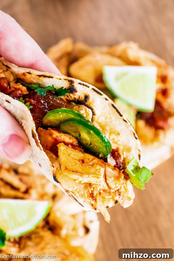 Shredded chicken carnitas in tortillas holding instant pot shredded chicken onion wrapped in tortillas
