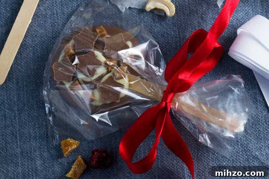 Chocolate Lollipops Recipe: Make Homemade Chocolate Pops 3 A chocolate lollipop packaged in a clear food bag with a red ribbon tied around it on a blue background.