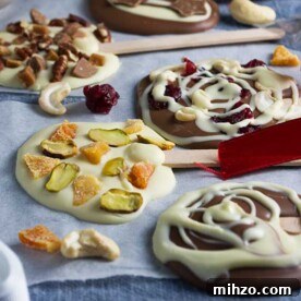 Chocolate Lollipops Recipe: Make Homemade Chocolate Pops 5 Homemade chocolate lollipops decorated in different ways lined up on baking paper and a blue cloth