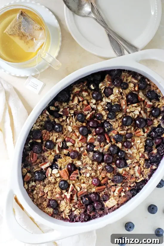 Wholesome and filling, this baked blueberry and apple oatmeal is a family favorite! Sweetened with maple syrup and packed with fresh fruit, it's a delicious and simple healthy breakfast! A baking dish of Baked Blueberry Apple Oatmeal with tea to the side.