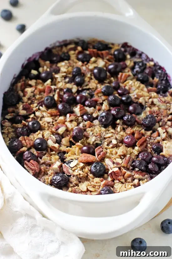 Wholesome and filling, this baked blueberry and apple oatmeal is a family favorite! Sweetened with maple syrup and packed with fresh fruit, it's a delicious and simple healthy breakfast! A white casserole dish filled with Baked Blueberry Apple Oatmeal.