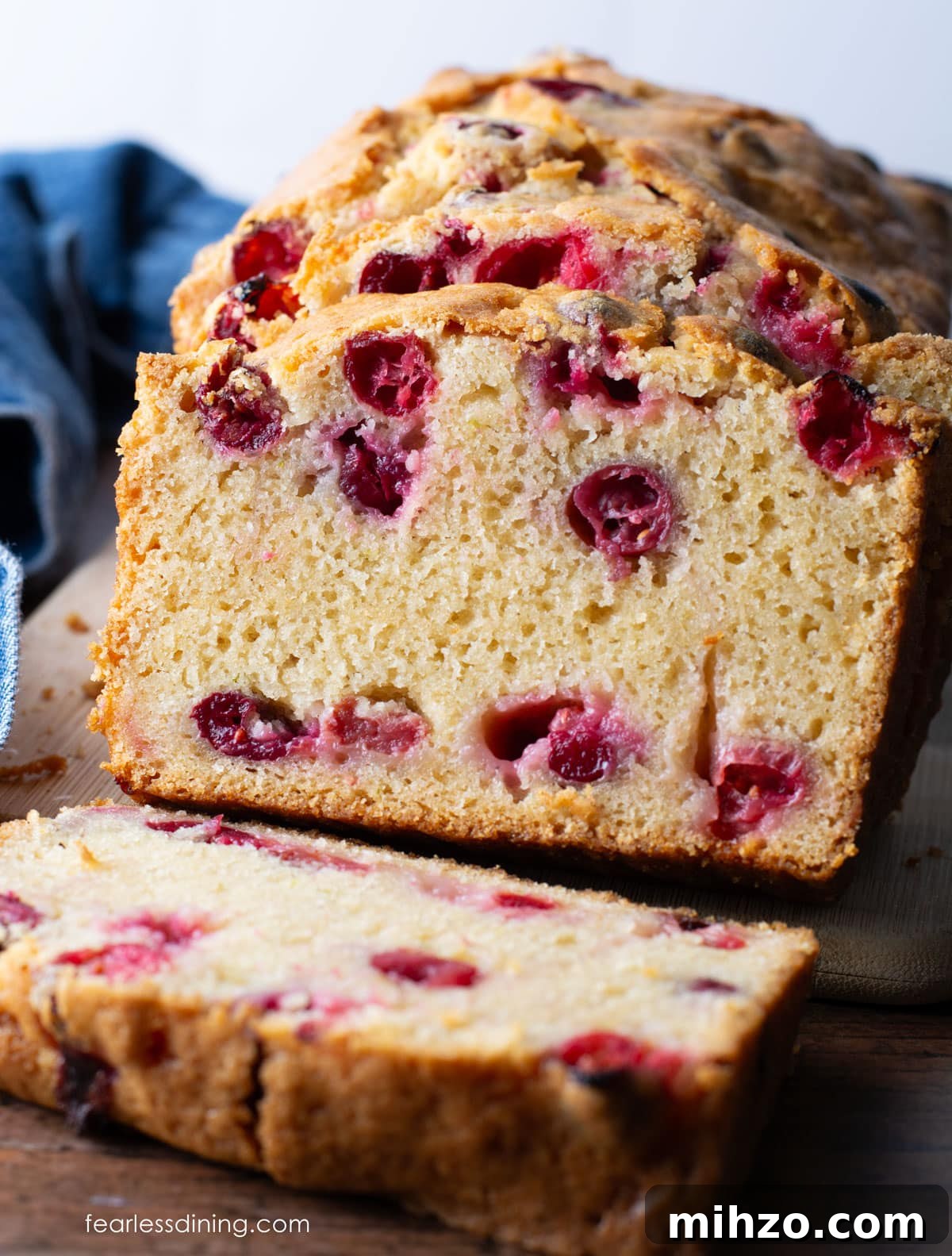 Gluten-Free Cranberry Pound Cake with Dairy-Free Option 2 The front view of a sliced gluten-free cranberry pound cake on a wooden cutting board.