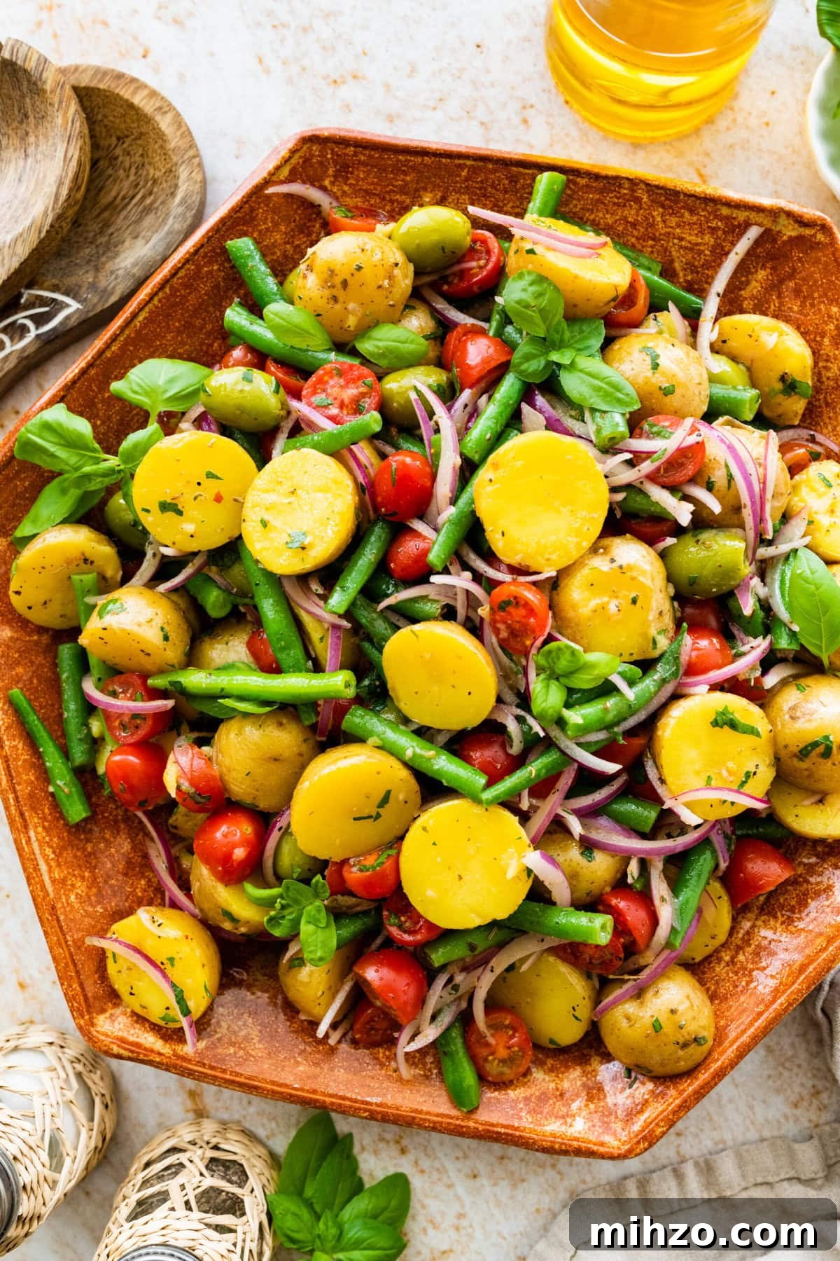 Italian Potato and Green Bean Salad Recipe 2 Close up of Italian potato salad in a wooden serving platter with wooden servers on the side.