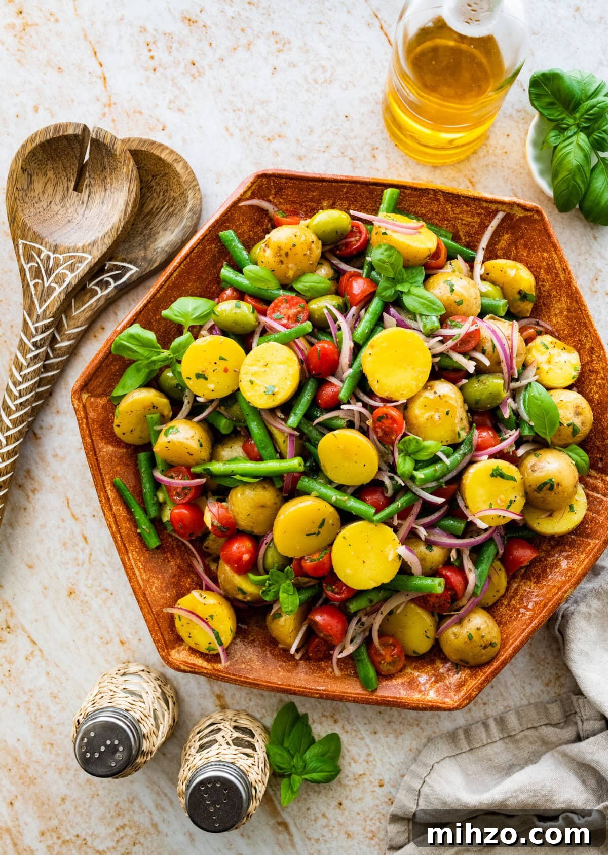 Italian Potato and Green Bean Salad Recipe 9 Italian potato salad in a wooden serving platter with wooden servers on the side.