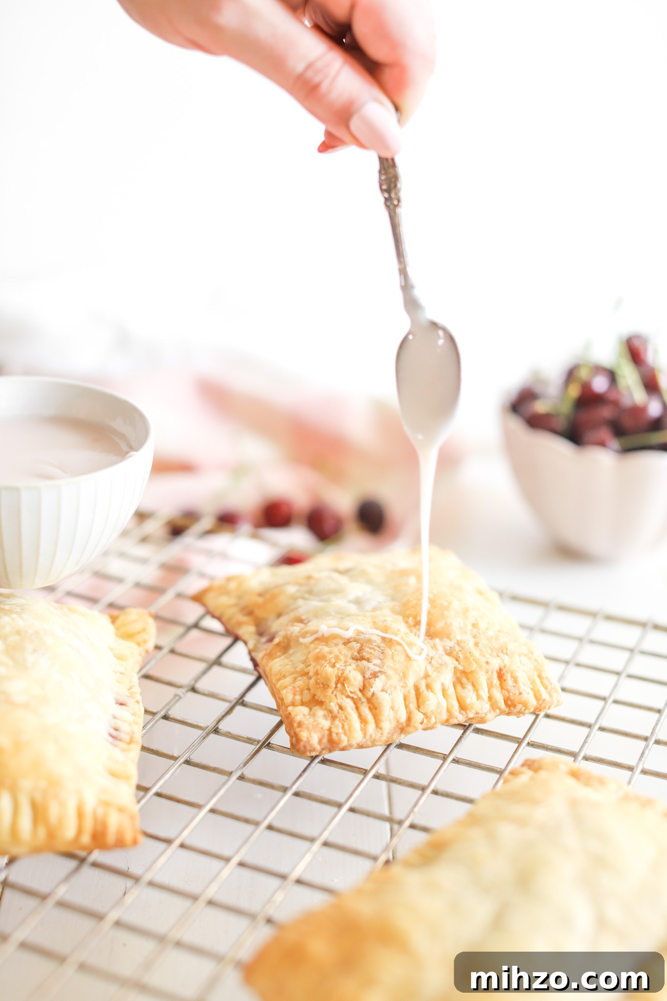 hand using spoon to pour glaze onto Cherry Pop Tarts by Fraiche Living