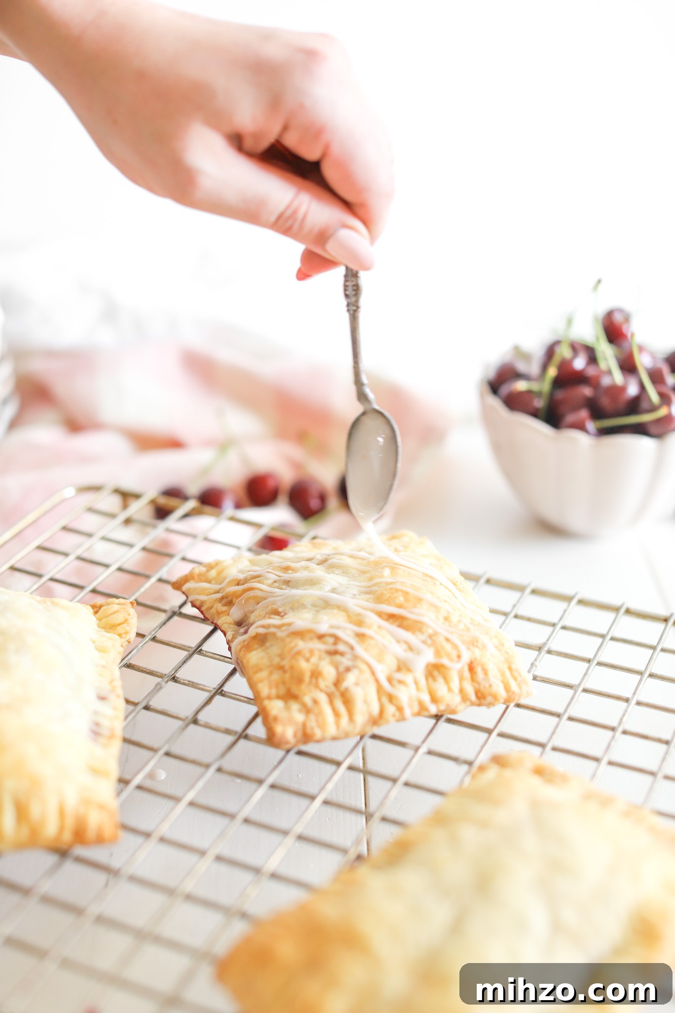 hand using spoon to pour glaze onto Cherry Pop Tarts by Fraiche Living